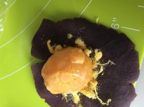 取红豆沙包入肉送和一个烤好的咸鸭蛋黄，全部包好滚圆