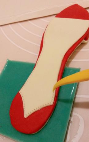 将其中一片浅黄色鞋垫干佩斯整体边边切小1毫米，鞋跟处切成尖角，用清水沾在红色鞋垫上面，尖形工具切出车线效果