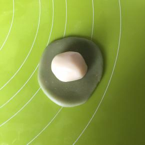 取一份水油皮，压扁擀圆，包入油酥