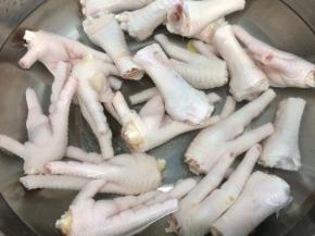 锅里倒入适量的水烧开，将一半黄酒和二片姜放入锅中，再将鸡脚放入悼水