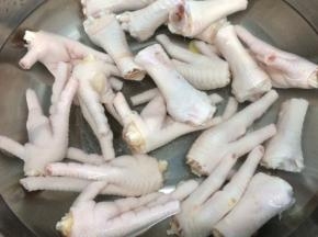 锅里倒入适量的水烧开，将一半黄酒和二片姜放入锅中，再将鸡脚放入悼水