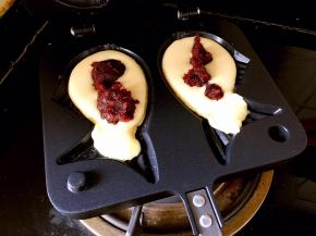 模具放到灶具上开最小火，倒入一半的面糊，用勺子加一勺豆沙在面糊上。