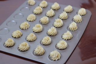 5.裱花嘴放入裱花袋中，将裱花袋套在杯子中装入面糊，用刮刀将面糊推向裱花嘴的位置，逆时针挤出曲奇花型