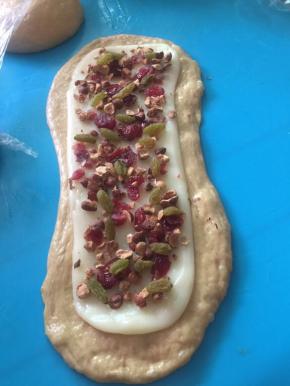 4个面团按扁排气擀成长舌状，麻薯团均分成4份也擀成比面团小一点的长舌状，摆上自己喜欢的干果坚果类，由上卷起按压至下卷实，收口朝下摆好在烤盘里