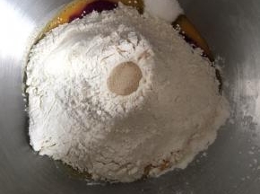 再倒入面粉，面粉中间挖一个小坑，倒入干酵母粉，启动低档进行和面