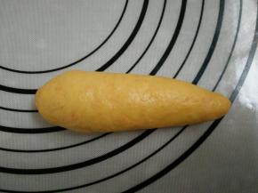 9.面团上下两边向中间对折。用手将一端搓成尖角状