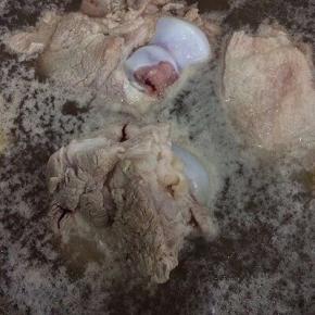 锅里倒入适量的水、料酒、姜和大骨焯水，去除血水