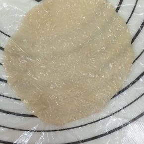 将剂子上面放上保鲜膜，用擀面杖擀成圆片