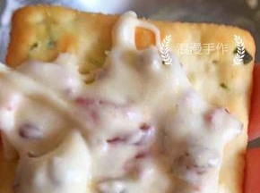 10，趁热用饺子馅勺挑起适量的牛扎糖抹在一片苏打饼干中心，再快速合上另一片苏打饼干。