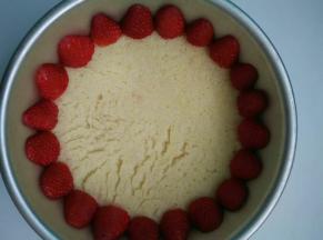 把油纸放入模具底层，上面放上蛋糕胚，四周摆一圈草莓（草莓去蒂一分为二）