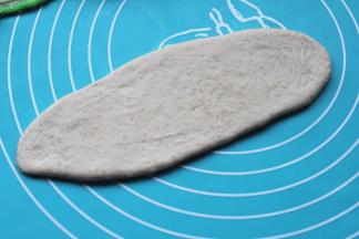 取一份面团擀成椭圆的长面片。