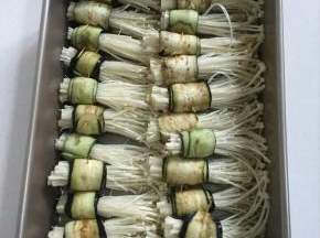 把卷好的茄子金针菇卷整齐地摆放在烤盘上！用刷子在表面刷一层油！