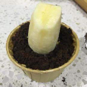 奥利奥饼干去掉夹心，用保鲜袋装起来擀碎，舀一勺奥利奥在杯子蛋糕上，当作泥土，香蕉切块，用牙签固定在蛋糕上