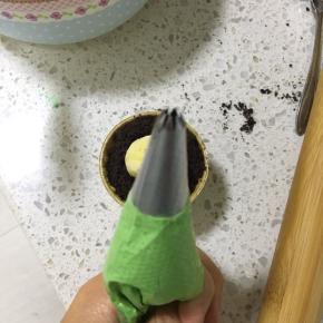 取出奶油霜，分成三份，其中一份少量的加入黄色色素，另外两份利用绿色色素和黑色色素调成深浅不一的绿色奶油霜，裱花袋中套入裱花嘴，绿色的用这个花型裱花嘴