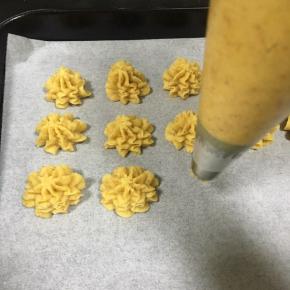 烤盘内铺一张油纸，裱花嘴90度垂直向下，挤出面糊，一边挤一边左右轻微晃动，注意力度均匀，最后顶部刻意顿一下提起，曲奇小花就裱好了