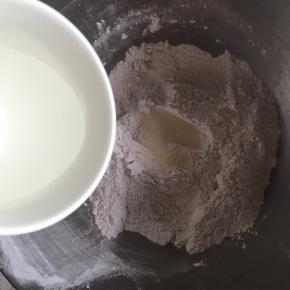 粉类混合均匀后，挖一个小孔倒入酵母，然后慢慢倒入水