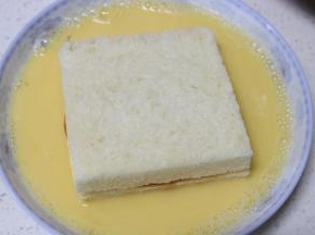 将摆好的西多士两面及四周均匀的粘上鸡蛋牛奶液