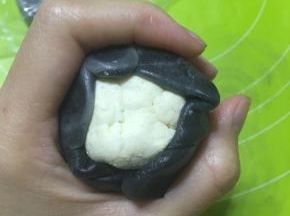 取切开的面卷压扁擀成饺子皮状，包住乳酪蛋黄馅，收口
