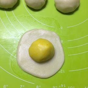 取一个水油皮，压扁，擀成饺子皮状，包入一个油酥