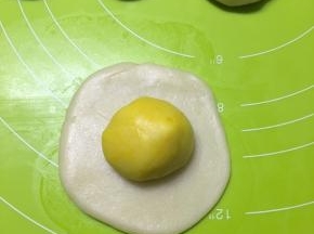 取一个水油皮，压扁，擀成饺子皮状，包入一个油酥
