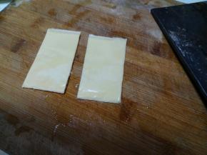 芝士片一分为二，分两次加入汉堡中。