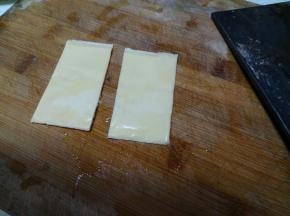 芝士片一分为二，分两次加入汉堡中。