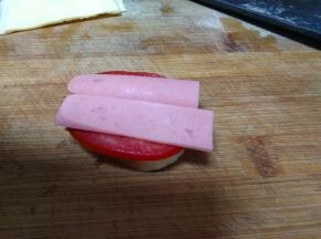 底部放面包片，然后在放西红柿、火腿肠、鸡蛋饼、芝士片、火腿肠、西红柿慢慢的放上面包片。