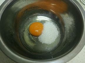 把鸡蛋打入小盆里，放入白糖。