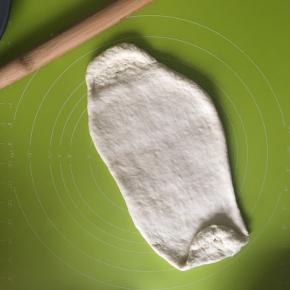 取出用擀面杖擀扁排出气体，然后滚圆，盖上保鲜膜松弛15分钟