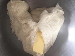 接着一直不停揉，揉成团后加入软化的黄油，继续揉搓