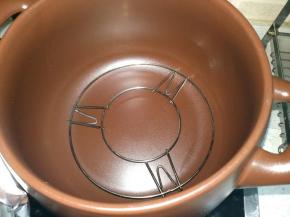 把烤架放在砂锅里面（烤架如果高了，可以把烤架脚折弯）。