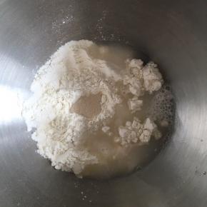 面桶内倒入高筋面粉，中间挖小孔，倒入活性干酵母，盐和糖对角线放置，倒入清水