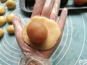 取一个饼皮按扁，包入一个莲蓉蛋黄馅（带一次性手套，比较好操作）