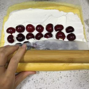 蛋糕从一边开始，卷起来一点，再利用擀面杖轻轻压着卷