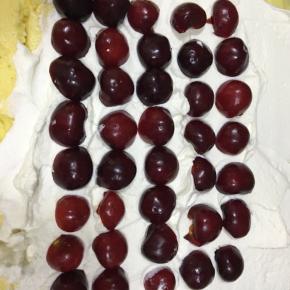 蛋糕凉后翻过面，把放在网架那一面朝上，抹上打发好的奶油，再均匀铺上大樱桃