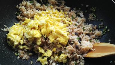 用木铲翻拌均匀，倒入玉米粒、炒好的鸭蛋。