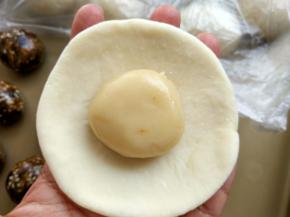 5. 取一只油皮，按扁，擀成圆形，放入一只油酥，包成圆形，收口朝下