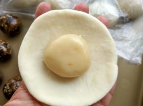 5. 取一只油皮，按扁，擀成圆形，放入一只油酥，包成圆形，收口朝下