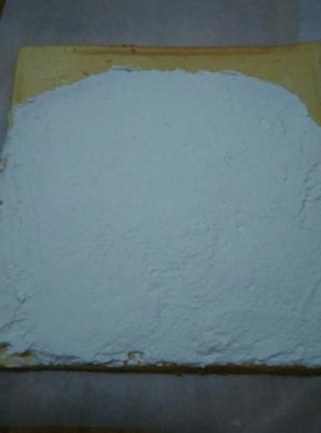 取一张干净的油纸，上面放上烤好的蛋糕卷，将打发好的奶油均匀的涂抹上，四周薄中间厚，末尾2厘米处不抹