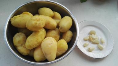 把土豆皮揭掉，剥好的蒜瓣洗净，用刀拍下切碎。