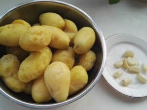 把土豆皮揭掉，剥好的蒜瓣洗净，用刀拍下切碎。