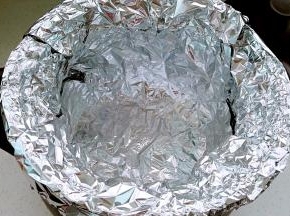 另一张锡纸也放入锅内，十字交叠成直筒状，一圈贴牢砂锅内壁，顶部包住砂锅边沿。