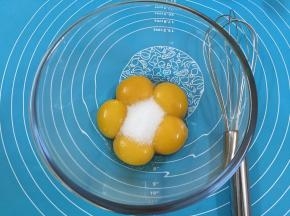2. 在蛋黄糊中加人细砂糖，用手动打蛋器搅拌