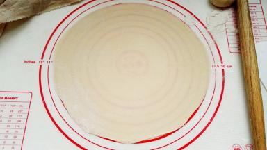 先取1个擀皮，其他的用湿布盖着防干皮。用小擀面杖擀成大小合适的圆形。