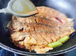 大火炖煮期间用铲子捞起汤汁浇到鱼身上，这个动作多重复几次，以便于鱼入味更快。
这时添加少许盐调味。
为防止粘锅，必要时用双手拿住锅柄，离火并转圈晃动锅。
炖约五分钟后大火收汁，汤汁变得浓厚即可。