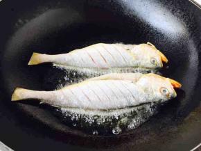 1，开大火，置锅，锅热，放入适量的油，当油温六成热时放入黄花鱼。
往热油锅里放鱼时请注意，要用双手拎着鱼的头和鱼尾，轻轻放入油锅里。
刚刚放入鱼后千万不要急于翻动，因为铲子是凉的，鱼肉会马上锁住铲子，也就是粘铲子。
煎约1分钟后，请观察鱼身边的颜色，如果发黄色，说明可以翻动。

