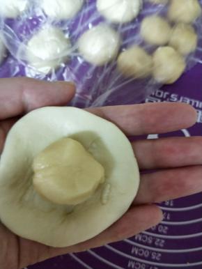 取一份油皮擀圆，包入油酥，收口捏紧，12份依次包好