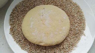 芝麻倒盘中，面剂沾水那面朝下，轻轻按一下，让芝麻粘满面剂