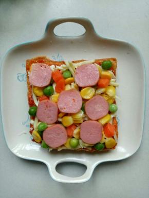 把胡萝卜玉米青豆用开水烫一下，摆在吐司上，再放上烤肠片，撒上黑胡椒粉，盐1小勺
