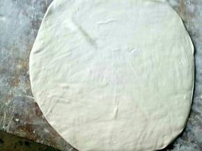 醒好的面团用擀面棍擀开，越薄越好